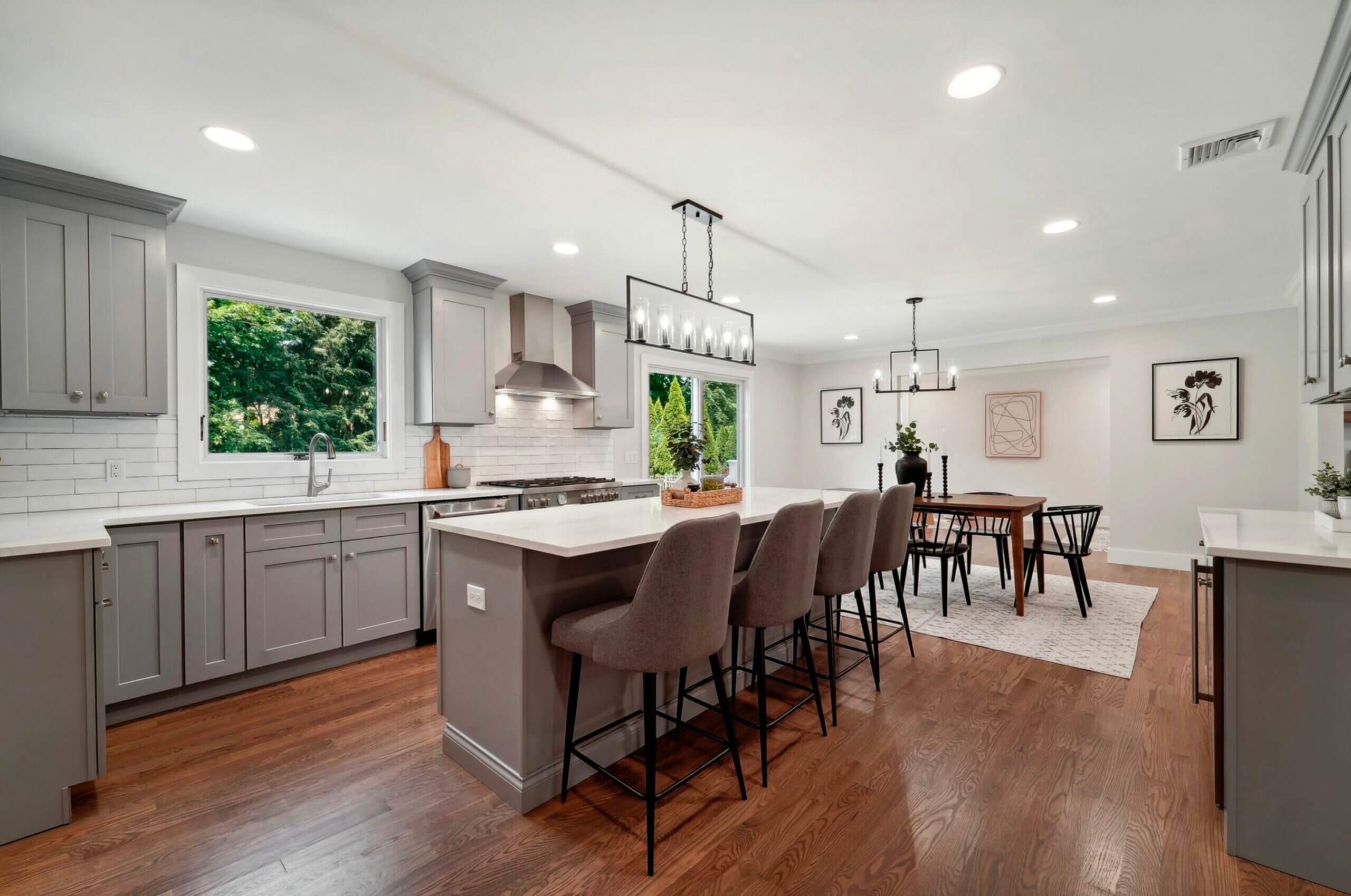 Modern kitchen with barstool seats, white marble countertops and stainless steel hood